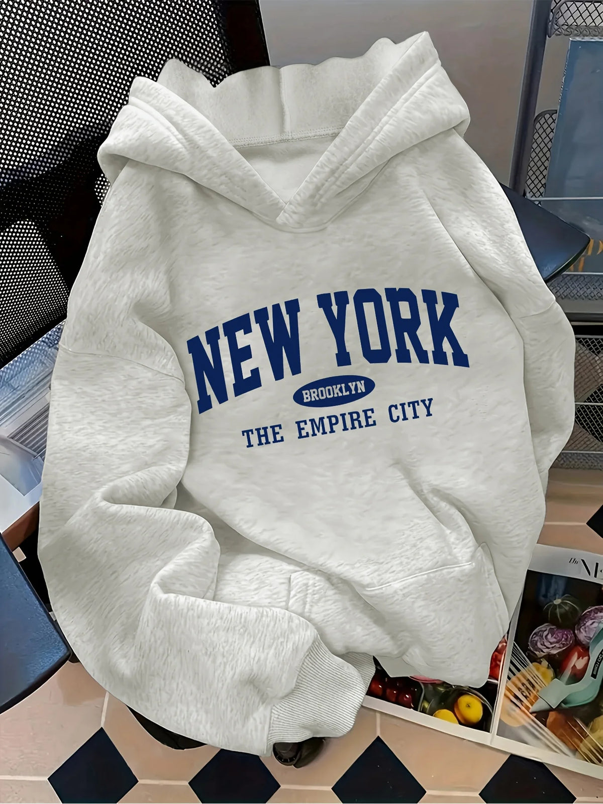 Oversized light gray hoodie featuring a blue "NEW YORK" graphic, kangaroo pocket, and ribbed cuffs.