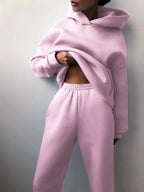 Cozy pastel pink tracksuit set featuring an oversized pullover hoodie and high-waisted jogger pants.