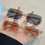Rimless Y2K rectangle sunglasses in gradient black and brown lenses, featuring gold metallic accents and slender temples.