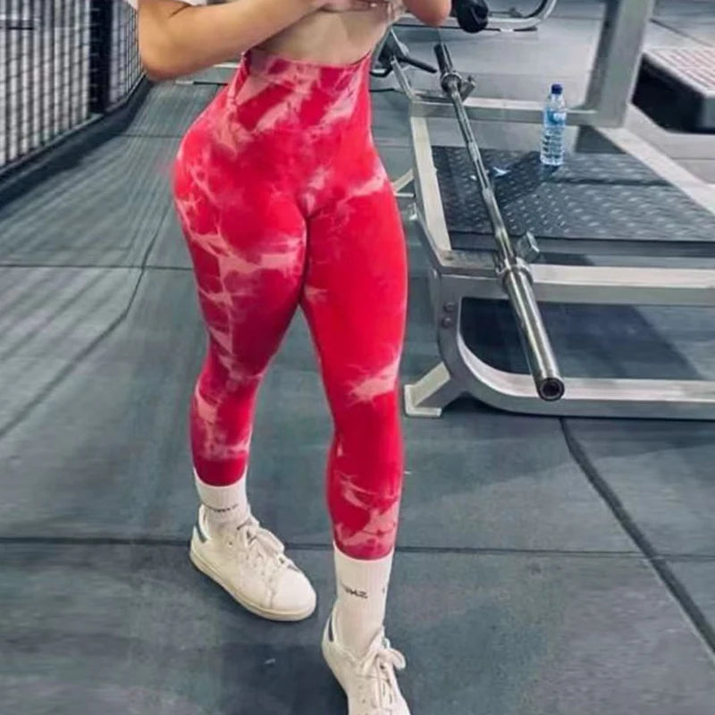High-waisted red tie-dye leggings with a seamless design, worn by a model, paired with white sneakers and socks.