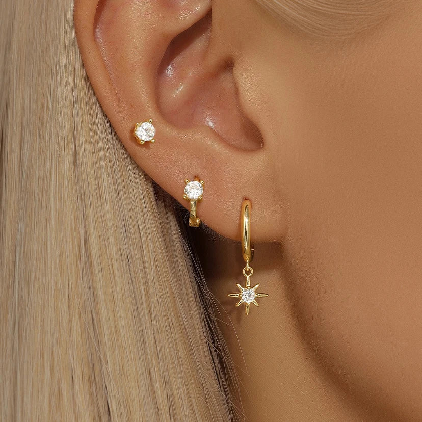 Asymmetric 3-piece earring set featuring gold-tone geometric hoops and star-shaped drops, worn in multiple piercings.