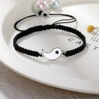 Black braided bracelet with a white and black Yin Yang enamel symbol, featuring an adjustable knot closure.