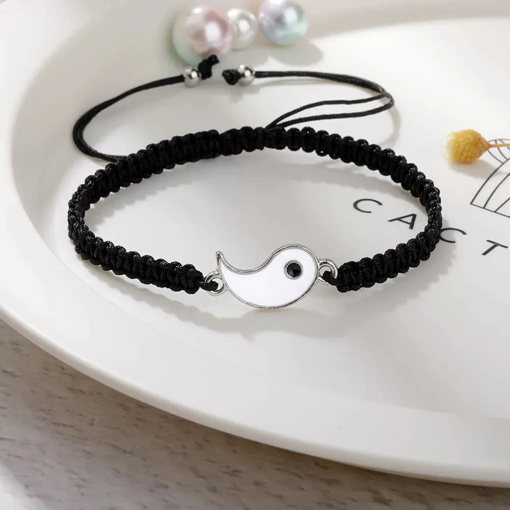 Black braided bracelet with a white and black Yin Yang enamel symbol, featuring an adjustable knot closure.