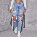 High-waisted distressed straight-leg denim jeans in light blue, featuring large rips and raw edges, paired with white sneakers.