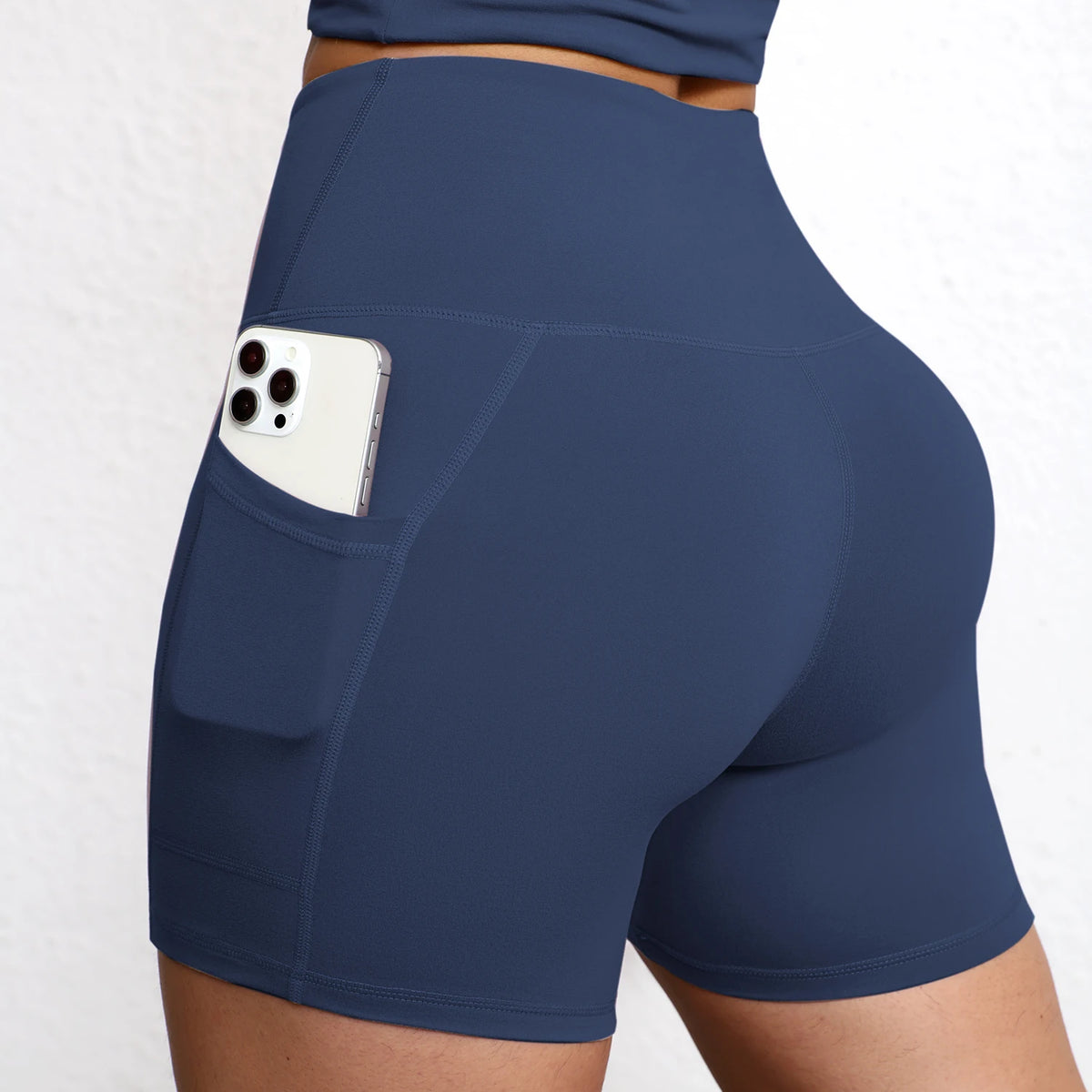 High-waisted navy seamless yoga shorts featuring side pockets and a supportive waistband for a secure fit.