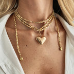 Vintage layered necklace with golden square links and a large heart pendant, elegantly worn around the neck.