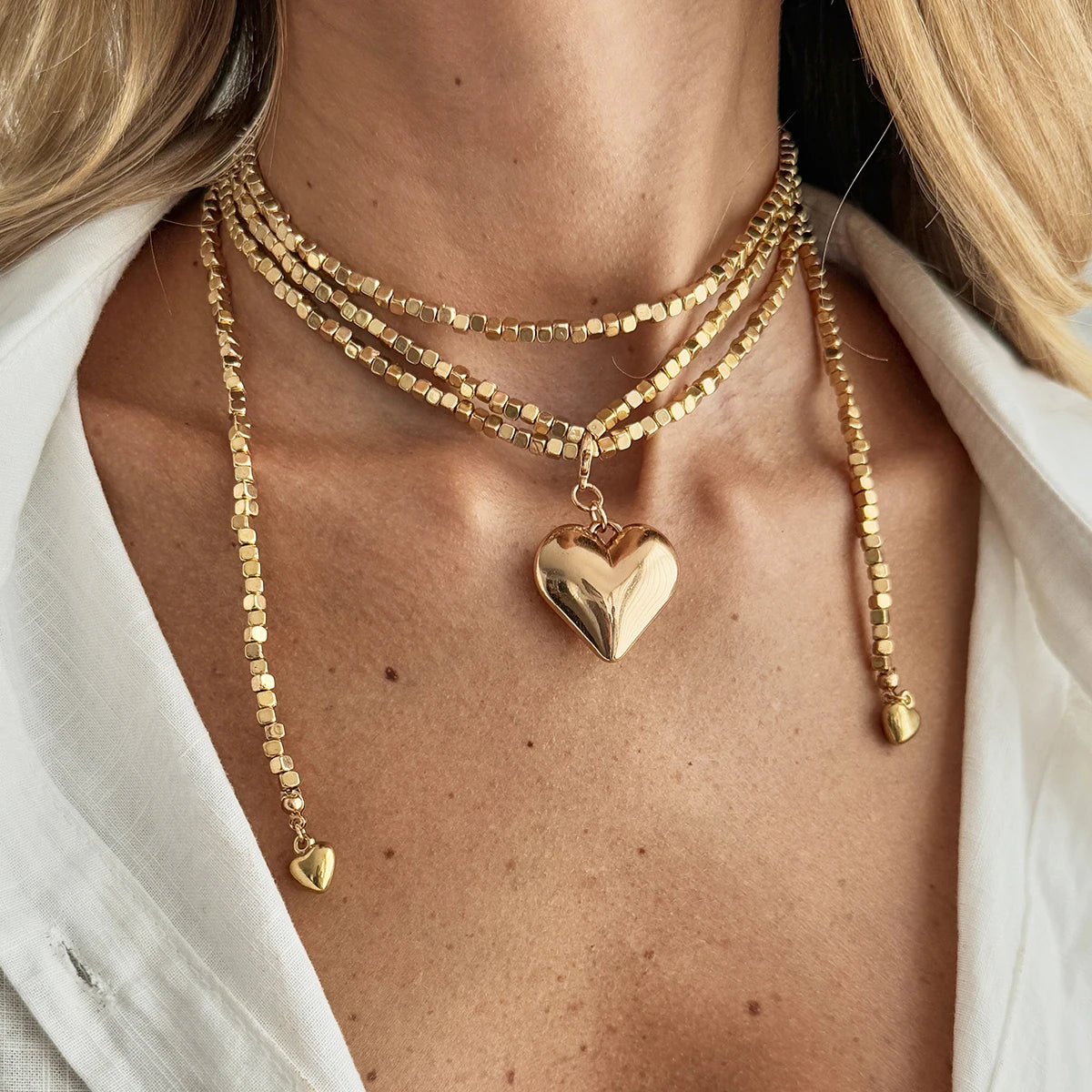 Vintage layered necklace with golden square links and a large heart pendant, elegantly worn around the neck.