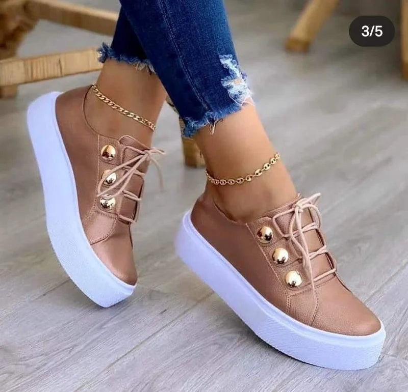 Classic leather platform casual sneakers in soft rose gold, featuring gold eyelets, paired with distressed denim jeans.
