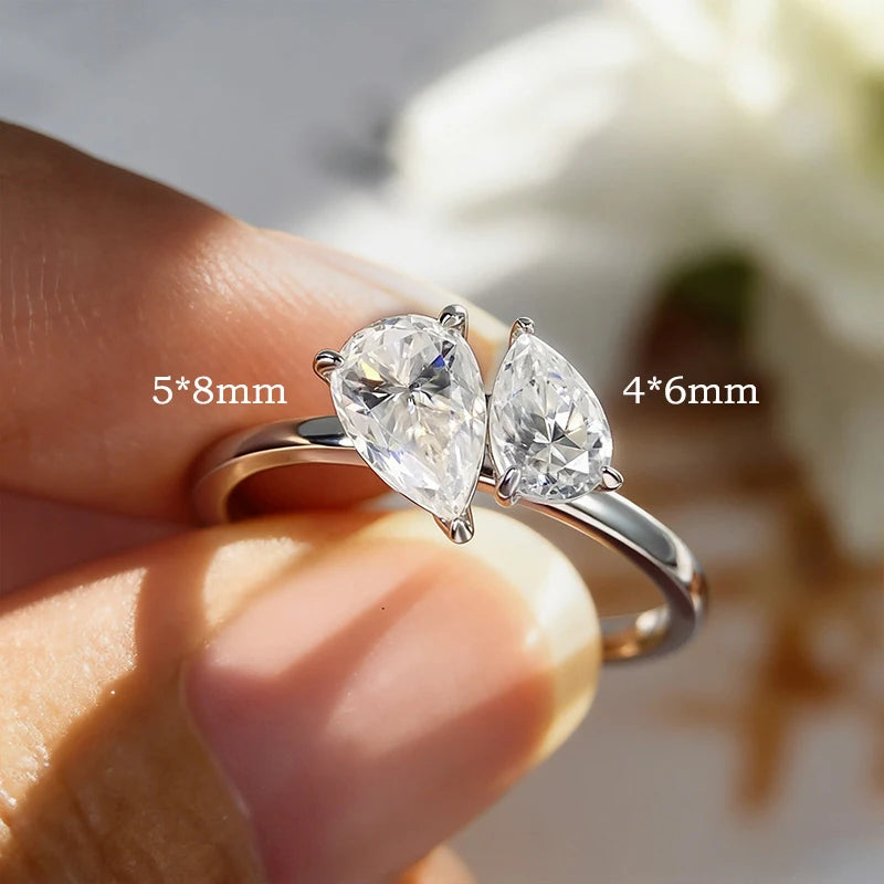 Sterling silver ring featuring two pear-cut Moissanite gemstones, one larger and one smaller, in an asymmetric design.