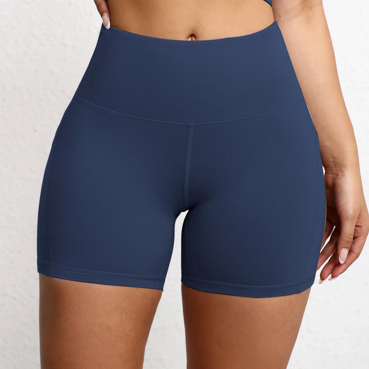 High-waisted seamless navy yoga shorts featuring a smooth fit and integrated side pockets for convenience.