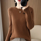 Cozy brown ribbed pullover with a crewneck collar, worn by a model holding a camera, set against a wooden backdrop.