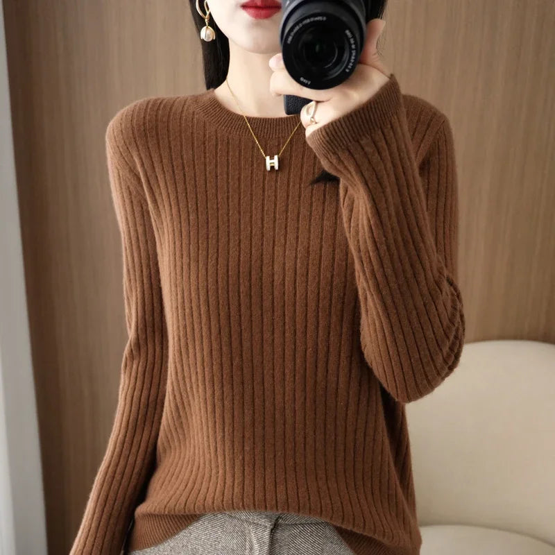Cozy brown ribbed pullover with a crewneck collar, worn by a model holding a camera, set against a wooden backdrop.