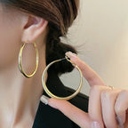 Chunky gold minimalist hoop earrings held by a model, showcasing their high-gloss finish and hollow design.