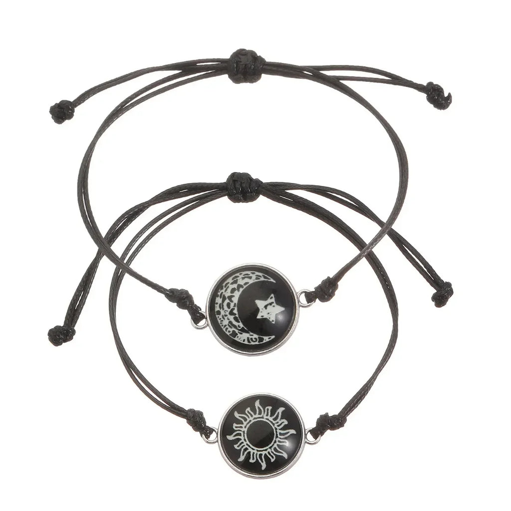 Two minimalist black rope bracelets featuring a sun and moon emblem, with adjustable sliding knots for a custom fit.