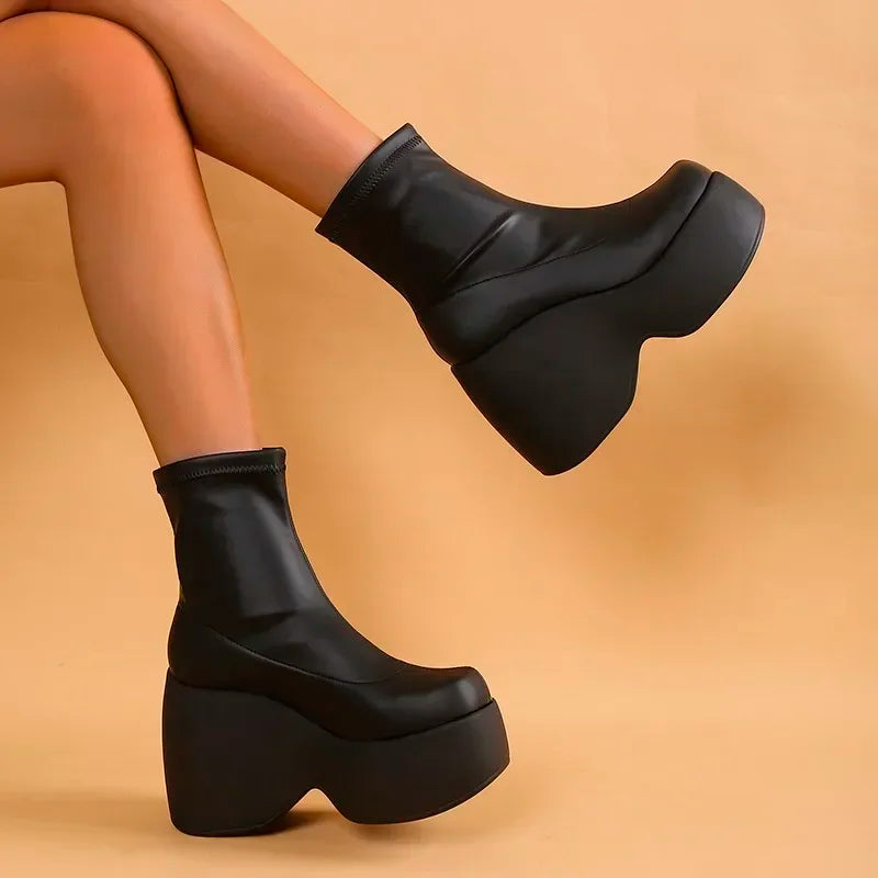 Ultra-chunky black platform boots with a curved block heel, made from sleek eco-leather, hugging the ankle.
