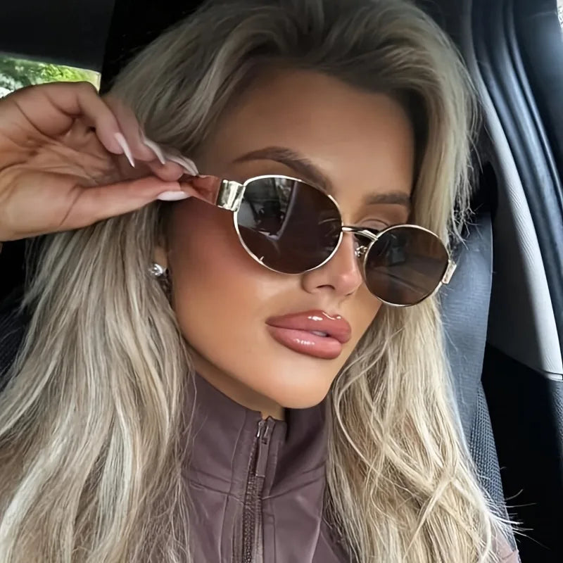 Hexagonal metal sunglasses with dark lenses, worn by a model in a brown zip-up top, showcasing a trendy, modern style.