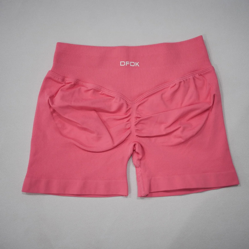 High-waisted, seamless gym shorts in a vibrant pink color with a scrunch-butt design and wide waistband.