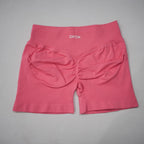 High-waisted, seamless gym shorts in a vibrant pink color with a scrunch-butt design and wide waistband.