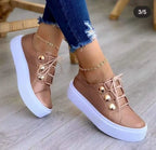 Classic leather platform sneakers in soft rose gold with shiny buttons, paired with distressed denim jeans.