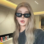 Chunky black cat-eye sunglasses with high-gloss finish worn by a model with long blonde hair, styled casually in a dark top.