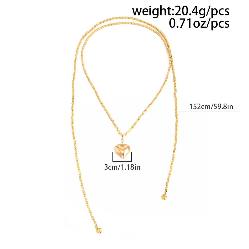 Vintage layered necklace with gold-tone metallic links, featuring a heart pendant and pearl accents.