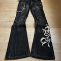Baggy distressed denim jeans in dark wash with embroidered design, wide-leg cut, and silver chain detail on the side.