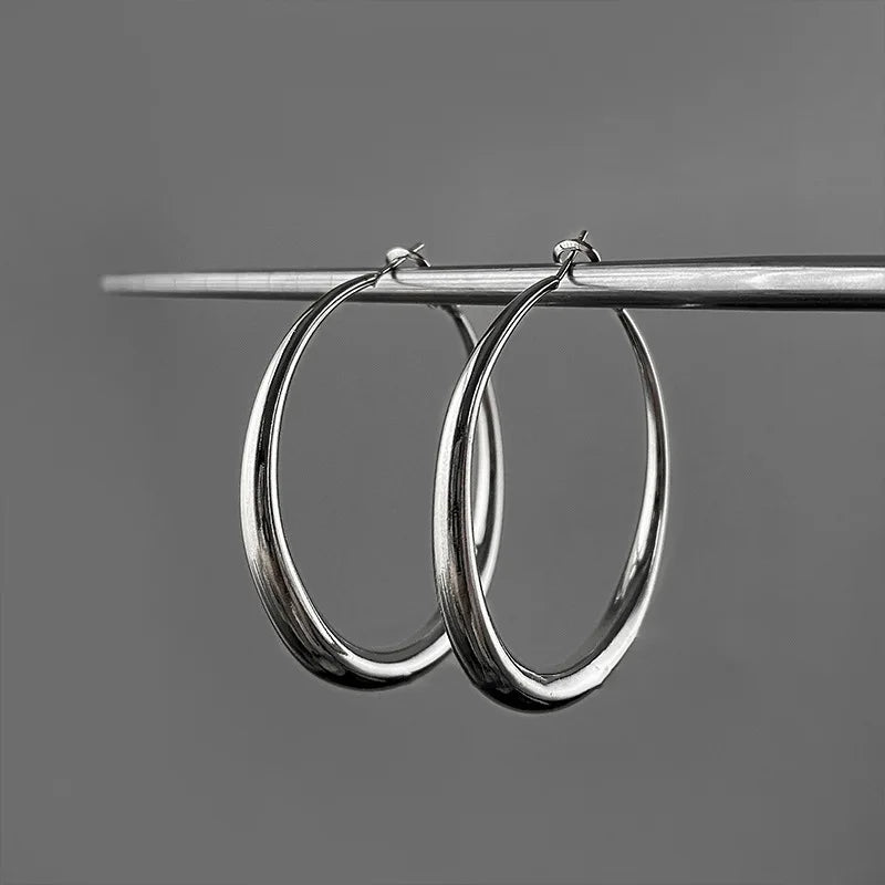Chunky minimalist hoop earrings in high-polished silver, featuring a hollow tubular design and secure snap-latch closure.