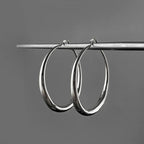 Chunky minimalist hoop earrings in high-polished silver, featuring a hollow tubular design and secure snap-latch closure.