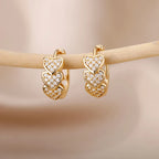 Chunky gold huggie earrings featuring three stacked heart designs adorned with clear enamel accents.