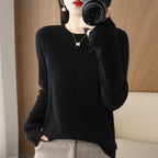 Cozy black ribbed pullover with a crewneck collar, paired with patterned trousers and a gold necklace.