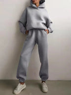 High-waisted gray fleece tracksuit set featuring an oversized hoodie and jogger pants, worn with white sneakers.