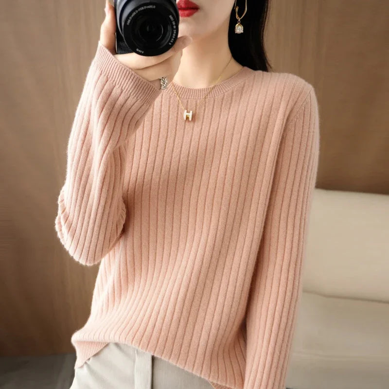 Cozy pink ribbed pullover with a crewneck, relaxed fit, and long sleeves, styled with a gold necklace and earrings.