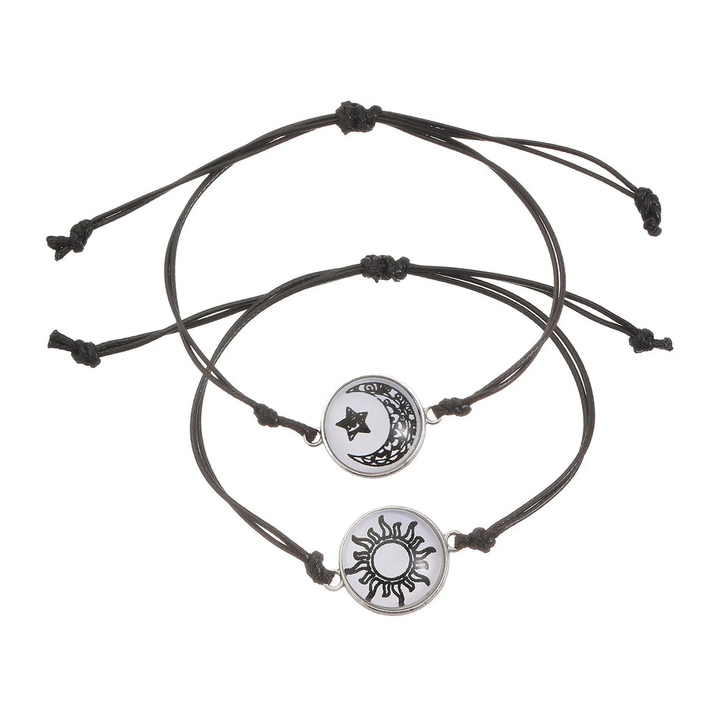 Two minimalist rope bracelets featuring a sun and moon emblem, designed with adjustable black cording.
