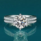 Round-cut Moissanite stone set in a high-polish 925 sterling silver band, featuring smaller stones on the band for added sparkle.