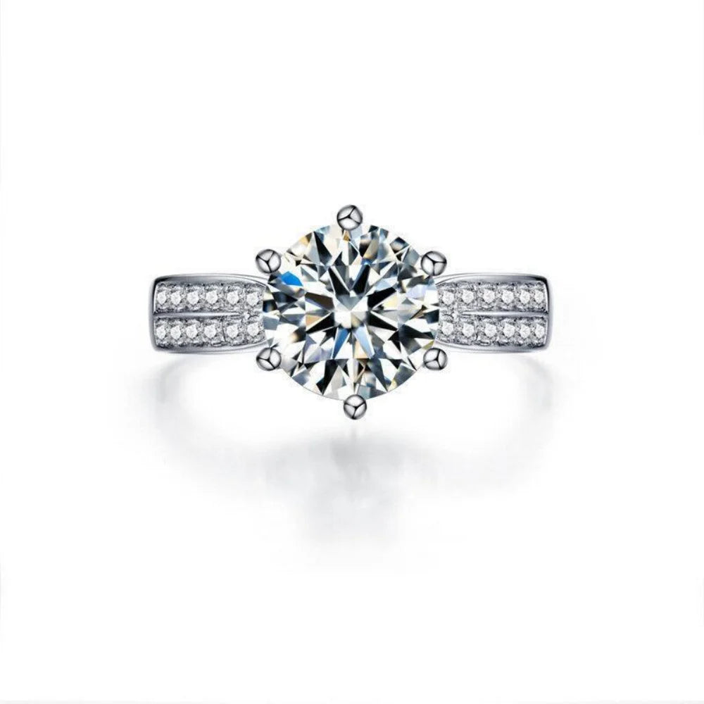 Round-cut Moissanite center stone surrounded by smaller stones, set in a polished 925 sterling silver band.