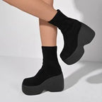 Ultra-chunky black platform boots with a sleek eco-leather finish, featuring a curved block heel and fitted ankle design.