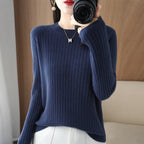 Cozy navy blue ribbed pullover with a crewneck; model is wearing it with white bottoms.