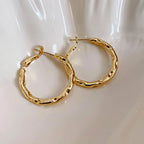 Chunky gold hoop earrings with a high-gloss finish and hollow tubular design, displayed on a white background.