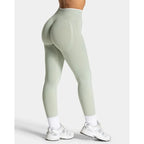 Seamless high-waisted leggings in light green, featuring contrast contour paneling, styled with white socks and sneakers.