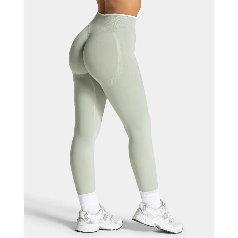 Seamless high-waisted leggings in light green, featuring contrast contour paneling, styled with white socks and sneakers.