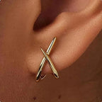 High-polish gold minimalist cross stud earrings worn in the ear, showcasing a sleek, modern design.