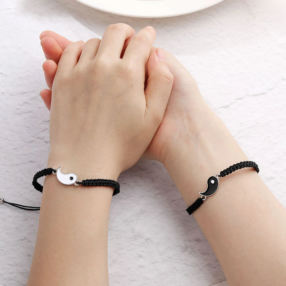 Matching couple bracelets in black and white, featuring woven nylon cords and interlocking Yin Yang symbols.
