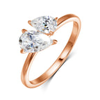 Rose gold ring featuring two pear-cut Moissanite gemstones in an asymmetric design, highlighting their brilliance and sparkle.