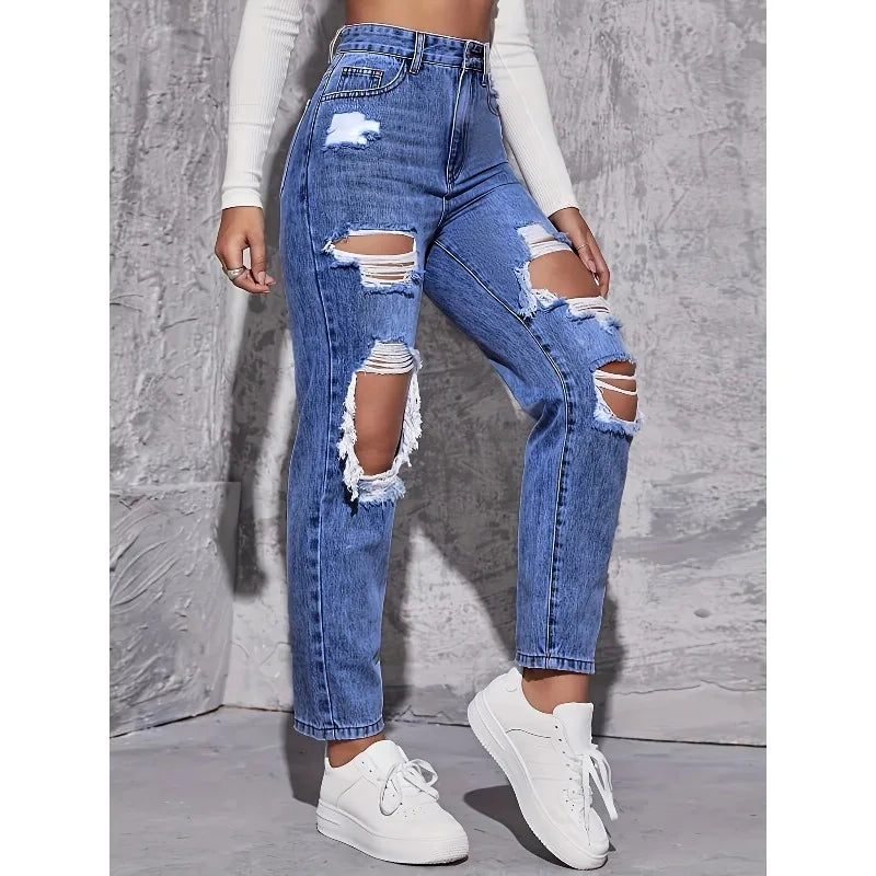 High-waisted distressed straight-leg denim jeans in light blue, featuring large rips, styled with a fitted top and white sneakers.