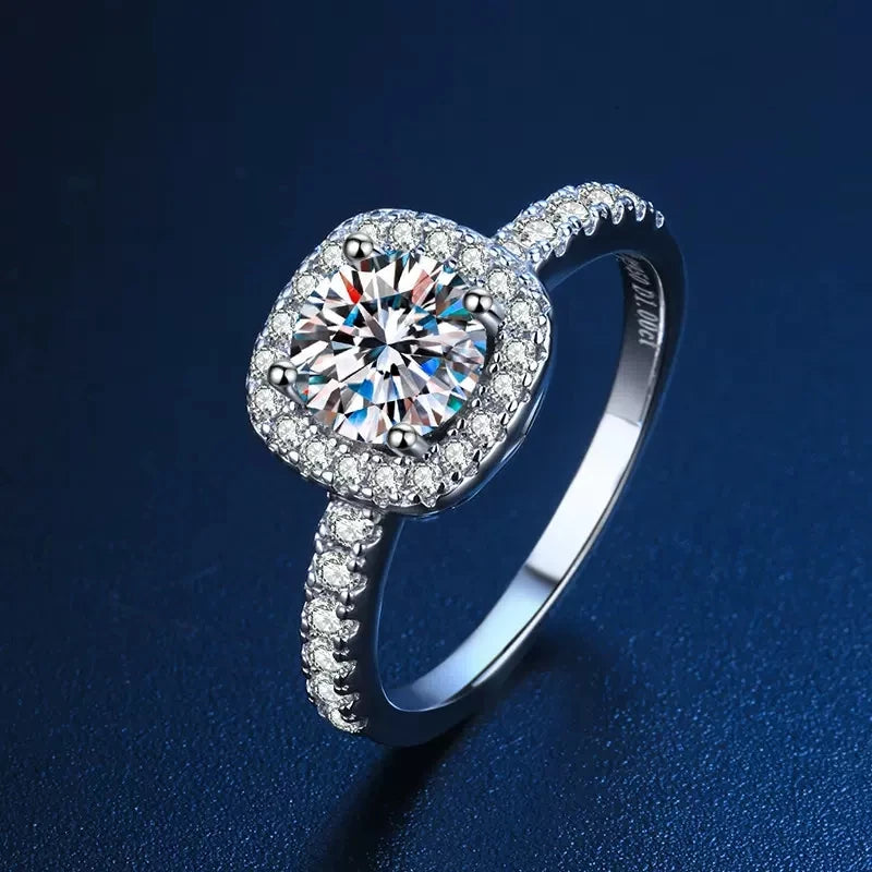 Round-cut Moissanite center stone set in a halo of accent crystals on a 925 sterling silver band.