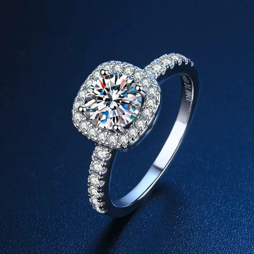 Round-cut Moissanite center stone set in a halo of accent crystals on a 925 sterling silver band.