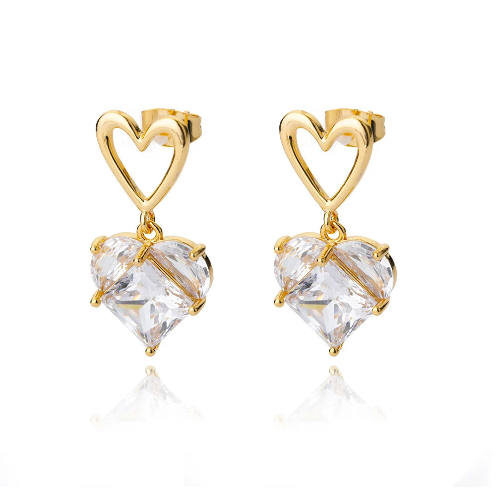 Chunky gold huggie earrings featuring a dropped clear heart charm, showcasing a modern minimalist design.