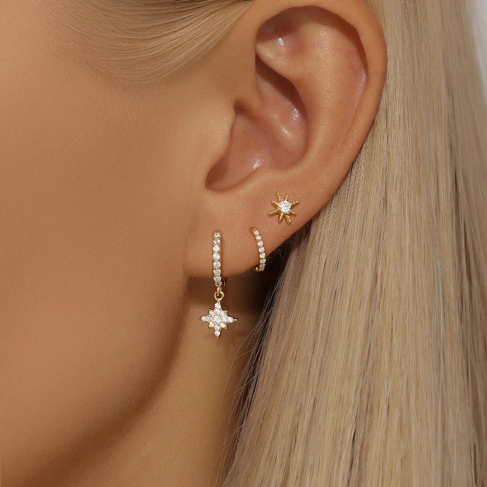 Three-piece earring set featuring gold hoop earrings, a star-shaped drop earring, and a small star stud with sparkly accents.