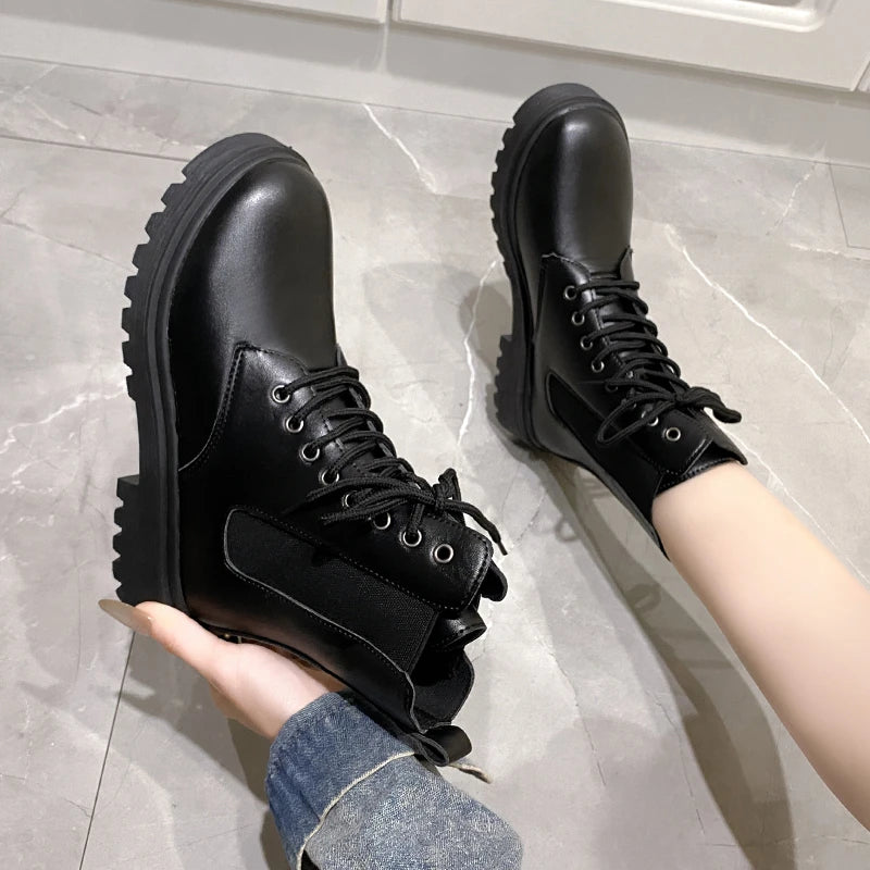 Croc-embossed black Chelsea boots with chunky sole and elastic side panels, worn with a hand holding one boot.
