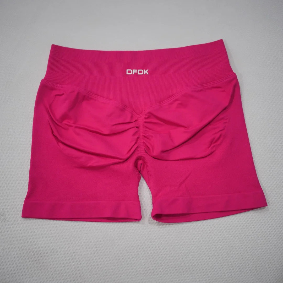 High-waisted gym shorts in a vibrant pink color with a scrunch design and supportive waistband. Lightweight, seamless fit.